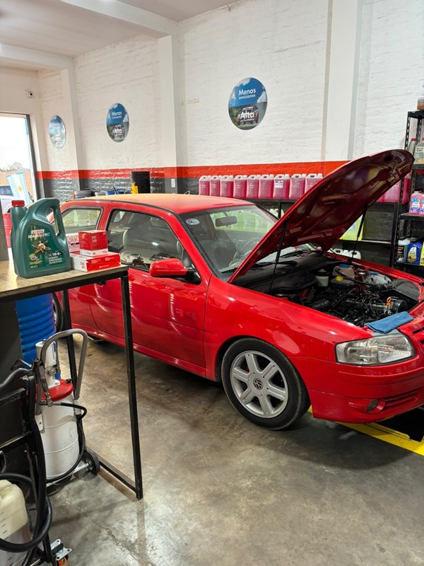 Volkswagen Gol rojo con el capó abierto en el taller