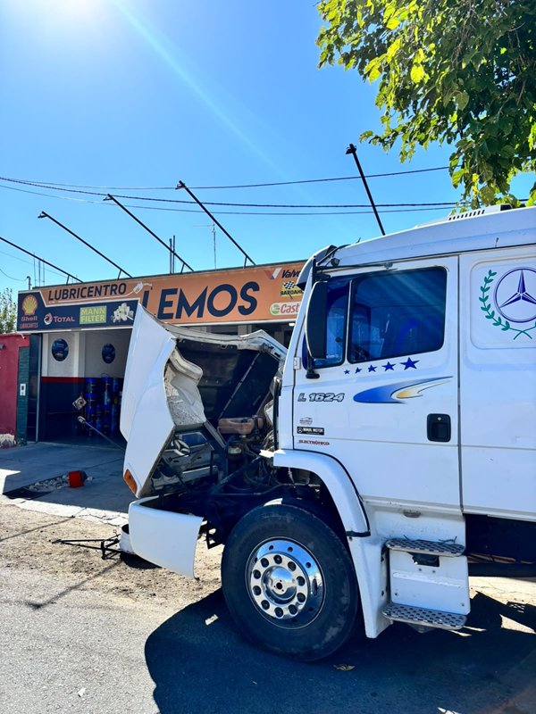 Camión Mercedes-Benz blanco con la cabina levantada frente a Lubricentro Lemos