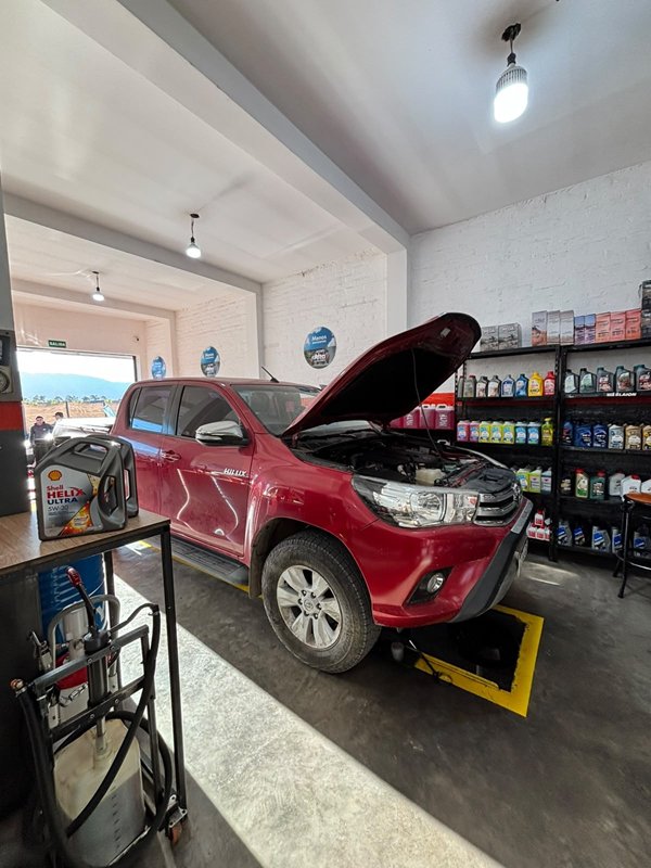 Toyota Hilux roja con el capó abierto en el box