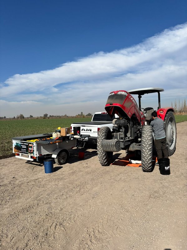 Tractor rojo y camioneta de servicio en un campo