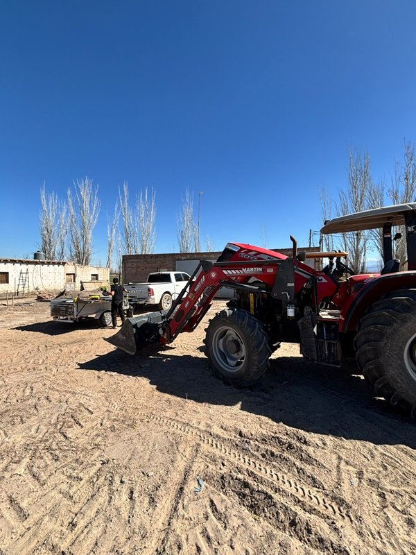 Tractor rojo con pala frontal durante un service a domicilio
