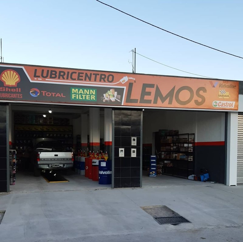Frente de Lubricentro Lemos de día, con el cartel naranja y las marcas Shell, Total, MANN-FILTER, Valvoline y Castrol