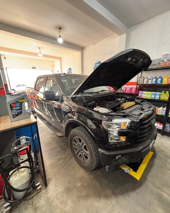 Interior del taller con una Ford F-150 negra y estanterías de lubricantes